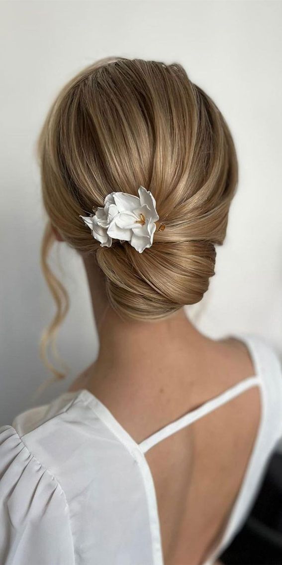 53 Best Wedding Hairstyles For 2023 Brides : Simple Low Bun With White Flower  Hair Pin With Fashionable Low Flower Bun For Long Hair (View 6 of 15)